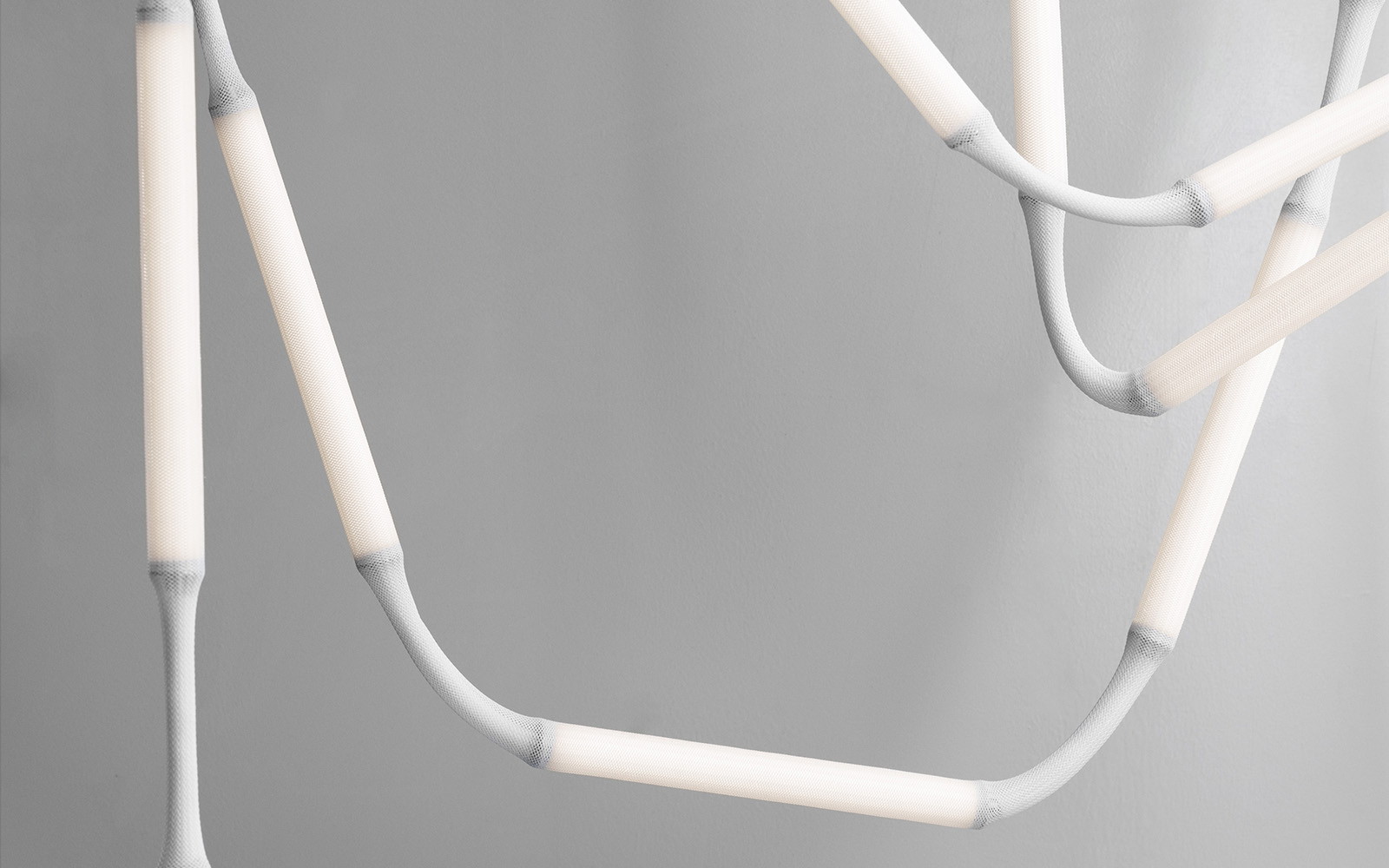 Close-up of Normann Copenhagen's Reb Lamp showing mesh fabric modules and metal tube base with integrated dimming function.